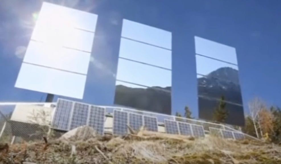 Three panel mirrors sitting on the side of. a mountain reflecting sunlight. 